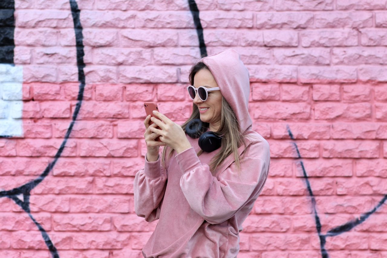 Model on monochrome,persons in front of wall woman in a pink blouse with glasses using social media.